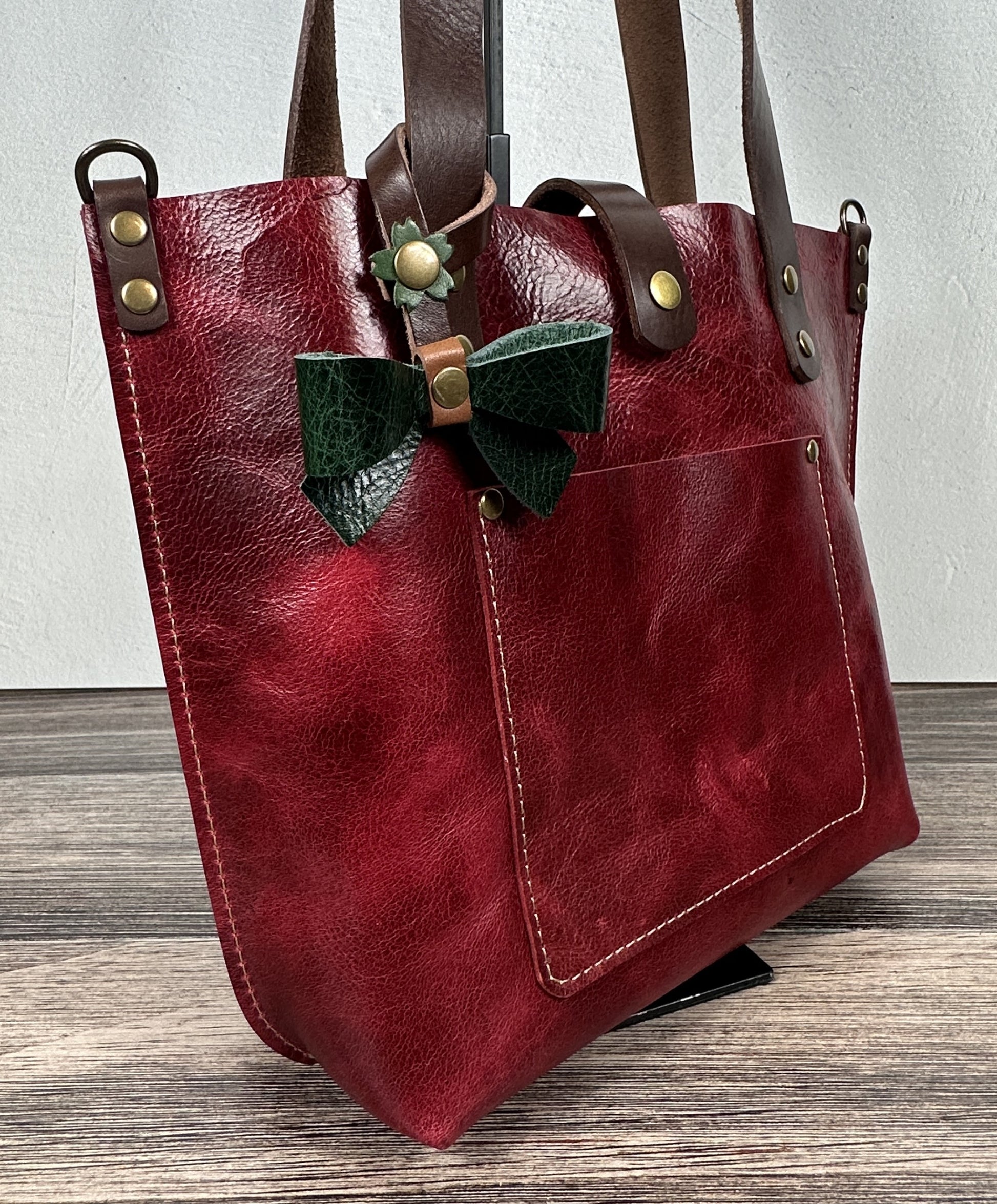 Green Leather bow bag charm clipped to a Red Leather Tote Handle – handcrafted purse accessory cut by hand.