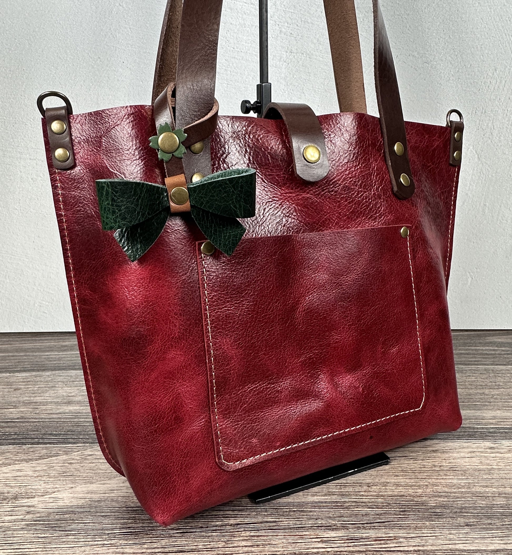 Green Leather bow bag charm clipped to a Red Leather Tote Handle – handcrafted purse accessory cut by hand.