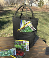 Waterman Bucket in olive green canvas bucket tote sitting on a wooden bench, functioning as a garden tool organizer. High-impact utility bag for home gardeners and hobbyists seeking durable handmade gear.