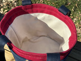 Interior of the Waterman Bucket Shorty is a small navy blue and red canvas bucket tote with long webbing shoulder straps. A versatile beach or pool bag handcrafted from 18oz cotton duck canvas for a classic nautical aesthetic.