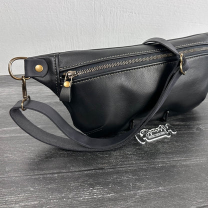 Side view of Leather Spinnaker Sling bag in Black with bronze hardware, Wickett & Craig Black English Bridle Leather Strap, and front zipper. Unisex slim crossbody sling handmade in Maryland.