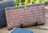 Close up view of the City Dock Wallet Fawn Burgundy and Amber Harris Tweed® Antique Brass Hardware.  The hardware has a scroll work detail.