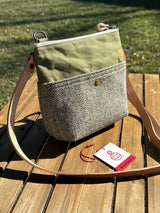 The Barra Crossbody is an Artisan-made vertical crossbody bag with two exterior magnetic slip pockets. The Barleycorn Harris Tweed and olive green waxed canvas create a sophisticated, heritage-inspired look for everyday carry.