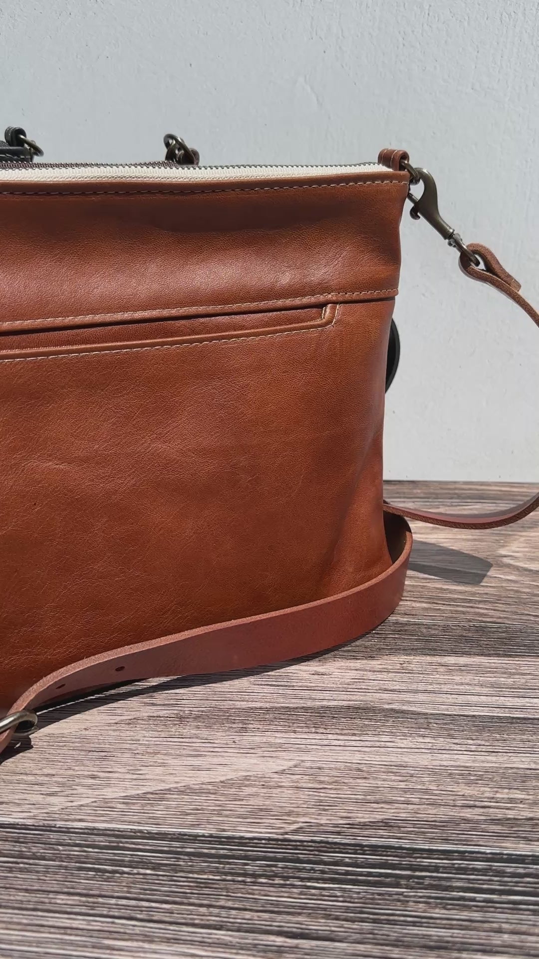 Video of a Group photo showcasing four handcrafted Leather Bayside Crossbody bags, each made with Horween leather in unique finishes. Bags are arranged to show variations in leather color and grain—Sienna, Vintage Dark Brown, Bomber Jacket Black, and Rustic Charcoal—each featuring solid brass hardware, a full metal zipper, and an adjustable vegetable-tanned leather strap. Designed and made in Maryland.